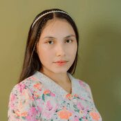 A young girl wearing a floral dress and headband.